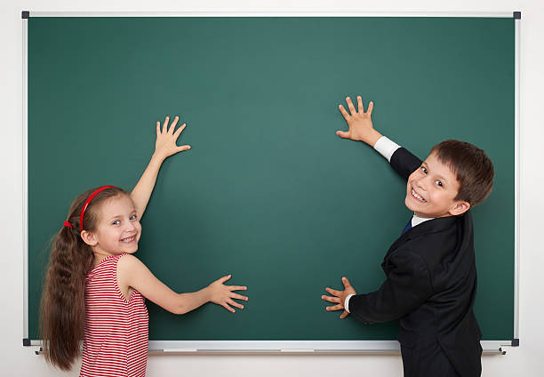 istock boy and girl write on school board 482974656