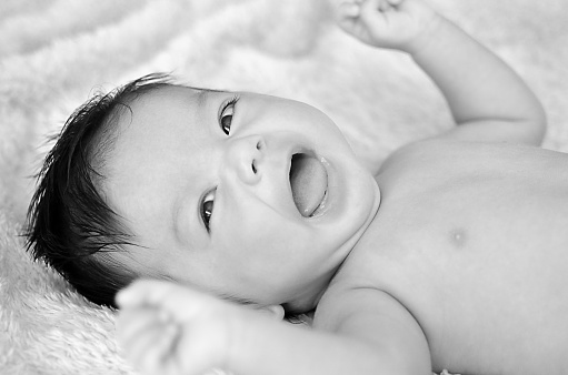 Black and white - naturally lit playful smiling baby looking at the camera.