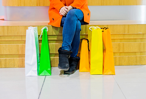 Asian woman holding shopping bags in shopping mall.