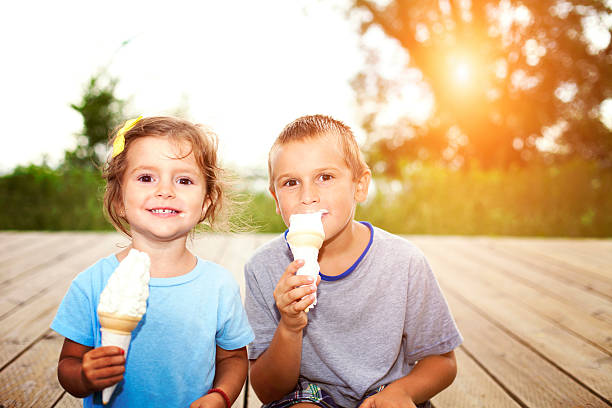 A child enjoys a delicious chocolate-coated ice cream with nuts on a sunny day. A refreshing and sweet moment in the heat.