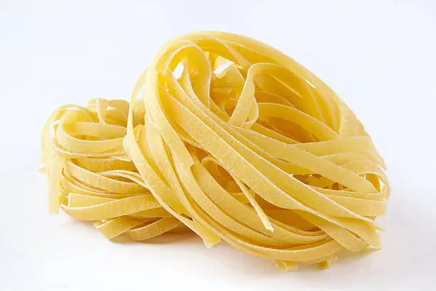 Italian pasta "Tagliatelle" isolated on white background. Pasta was carefully selected, it has natural curves, nest shape, and saturated yellow colour; because, it was made of egg.