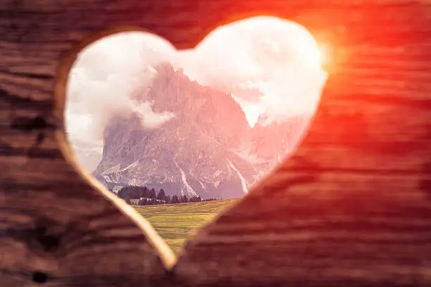Langkofel in background of wooden heart with sunlight - Dolomites - Italy
