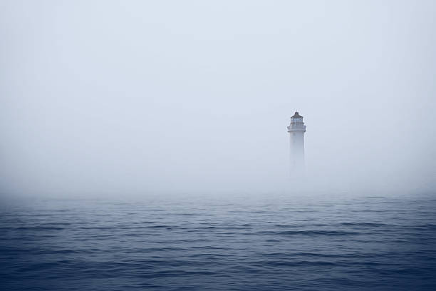 Lighthouse in foggy sea stock photo
