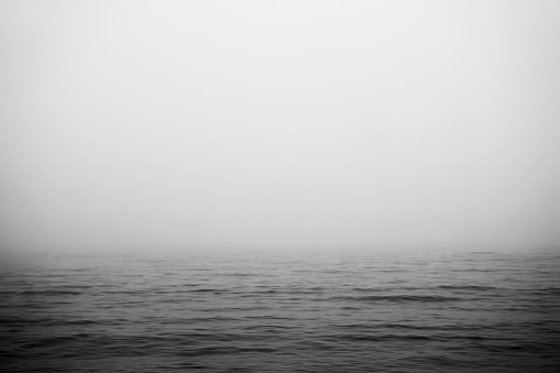 A lighthouse is barely visible as fog envelops Nova Scotian coastline.