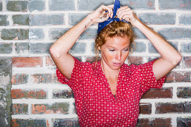 Young woman tying scarf on her head