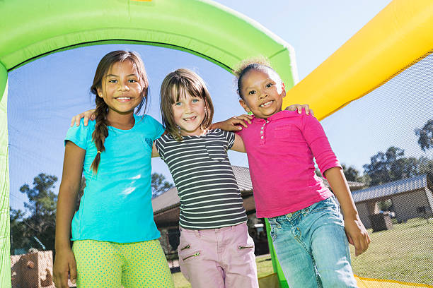 istock Multi-ethnic girls standing together on bounce house 482988242