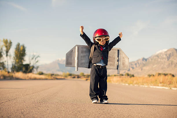 Young Boy Wearing Business Suit and Jet Pack Flies A young business boy is ready to take his business ideas to new levels in the stratosphere. kids goal setting stock pictures, royalty-free photos & images