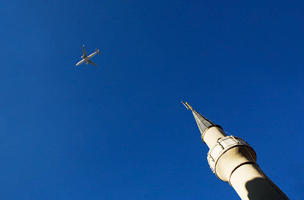 Plane and minaret on the sky background