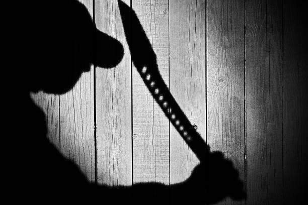 istock Human Silhouette with  Machete in shadow on wooden background, X 482992353