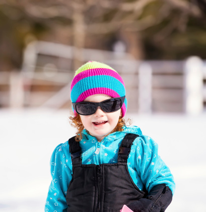 Little girl wearing sunglasses on a bright winter day.