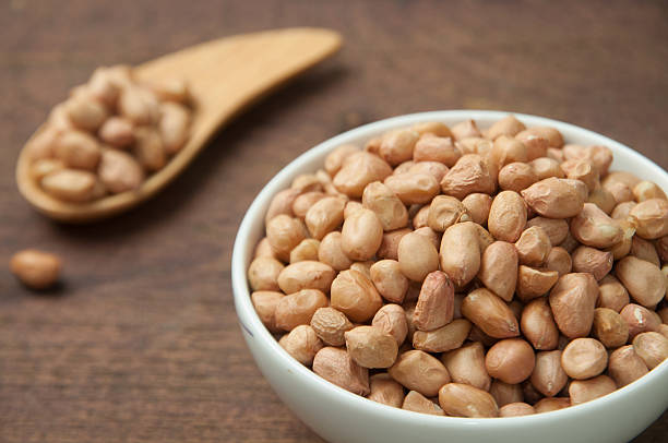 istock Raw peanuts in white bowl on wooden table. 482995044