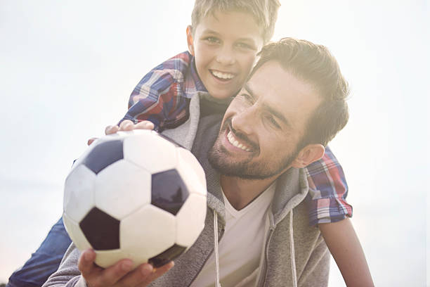 отец учит сына, как играть в футбол - team sport enjoyment horizontal looking at camera стоковые фото и изображения