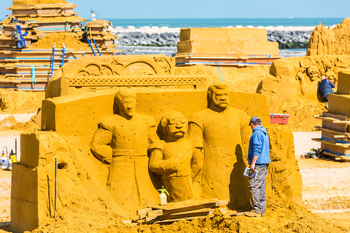 Ostend, Belgium - May 27, 2015: Sand Sculpture Festival «Frozen Summer Fun» 2015 at Ostend Beach, Belgium preparing. Curving artists are doing their job.