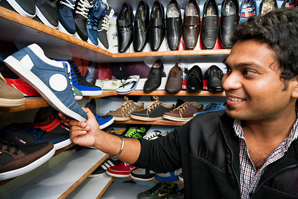 junger mann, kauf schuhe in einer shopping-mall - shoe men indian culture indian ethnicity stock-fotos und bilder