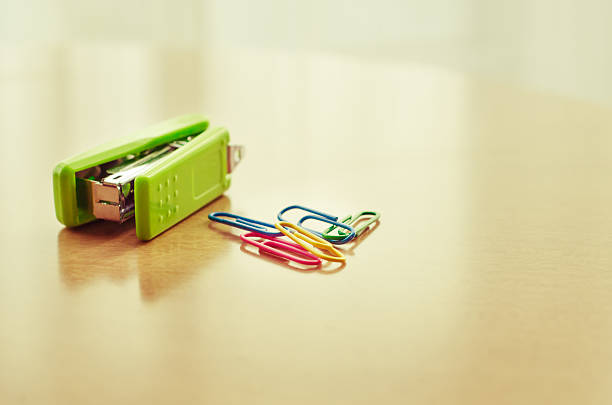 Green stapler and paper clip on table with blur vintage filter