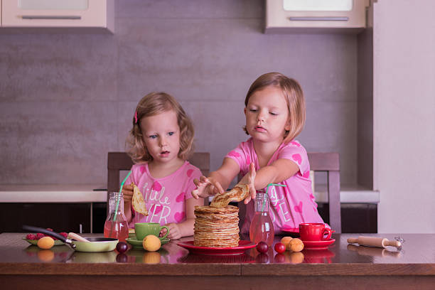 istock Pancake week. Little girls (sisters) eat pancakes. 483041414