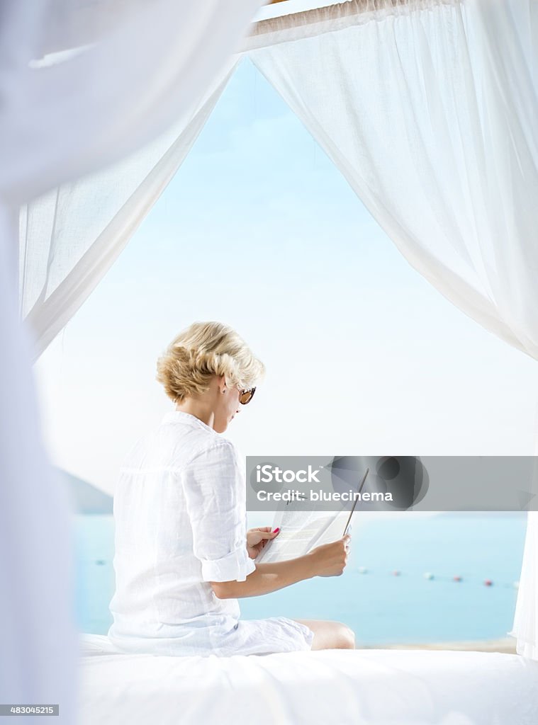 Mujer leyendo una revista en la playa - Foto de stock de Mujeres libre de derechos