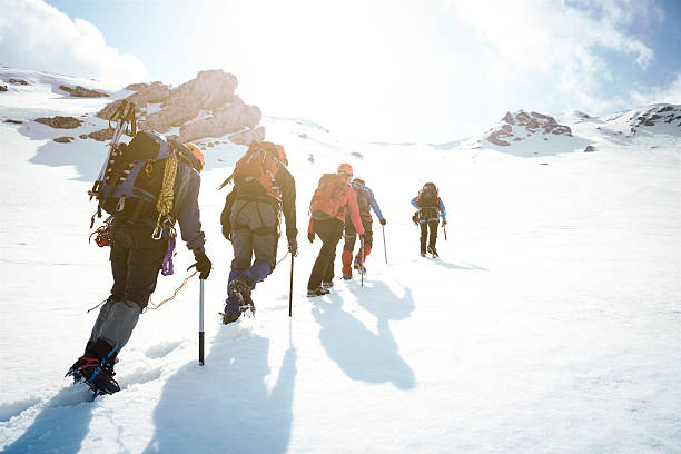 Mountaineering Group of mountaineers walking trough the mountains covered with snow. clambering stock pictures, royalty-free photos & images