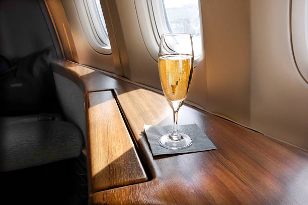 Welcoming Champagne A Glass of Welcoming Champagne awaits a First Class passenger on an Airline Flight window seat vehicle stock pictures, royalty-free photos & images