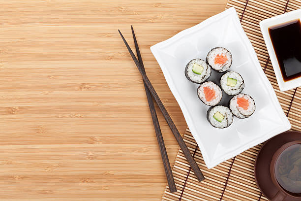 Sushi set, chopsticks and soy sauce over bamboo table with copy space