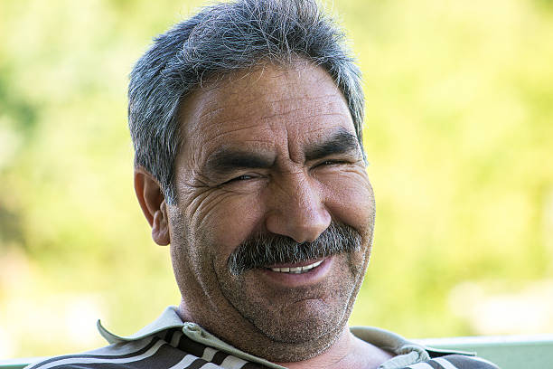 Laughing senior man looking at camera happily. Close-up portrait of senior adult man. Focus on man.