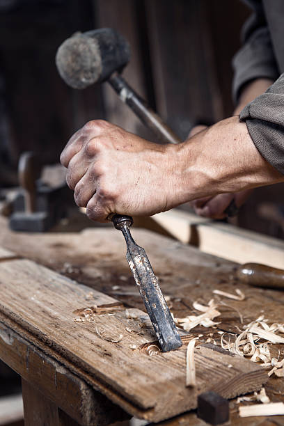 istock hands of carpenter with a hammer and chisel 483060024