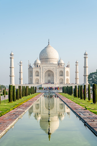 The famous Taj Mahal mausoleum with reflection in the pond, is one of the most recognizable structures worldwide and regarded as one of the eight wonders of the world. Clear blue sky, empty site without people. City of Agra, India.