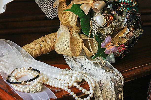 A bridal bouquet laying on the sand with a brooch