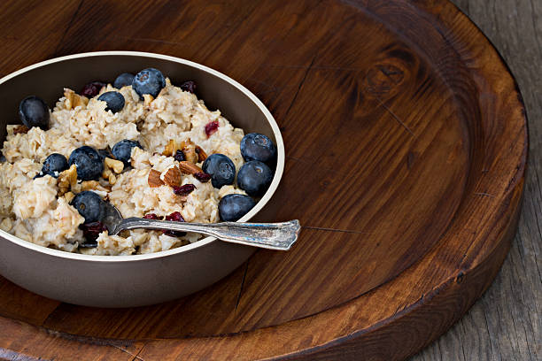 A high angle close up shot of a bowl of organic oatmeal on an old wooden tray.