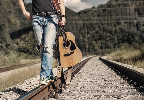 istock Mans legs in rippad denim walk on the railway 483082296