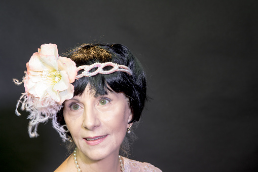 This attractive senior adult female is wearing a floral headband which was a popular accessory in the \