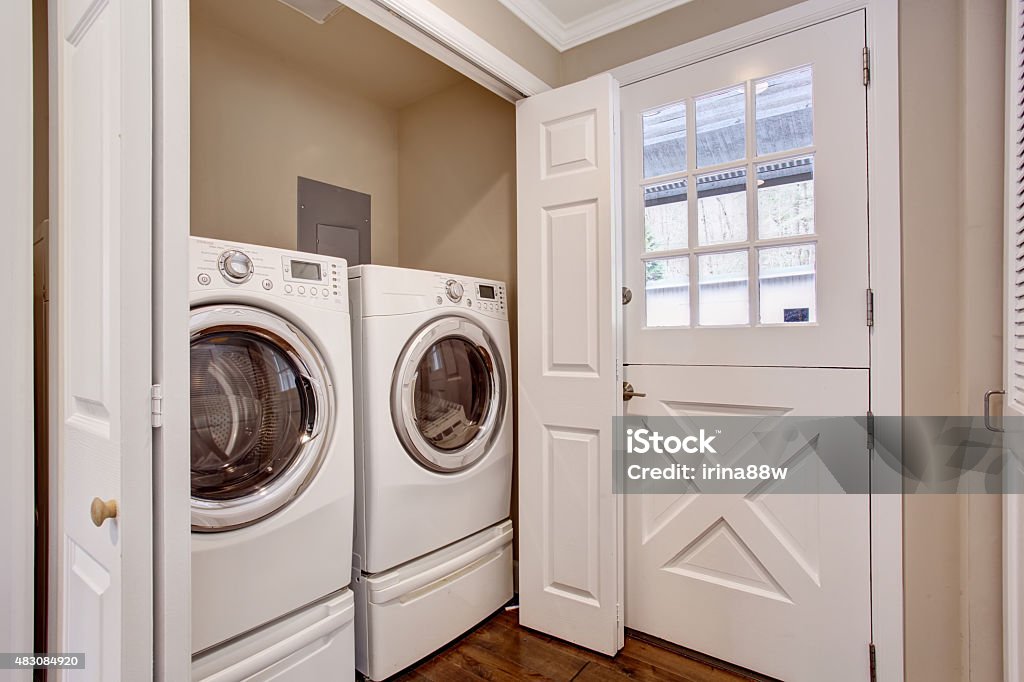 Small laundry area with washer and dryer. Small laundry room with hardwood floor, washer and dryer. Utility Room Stock Photo