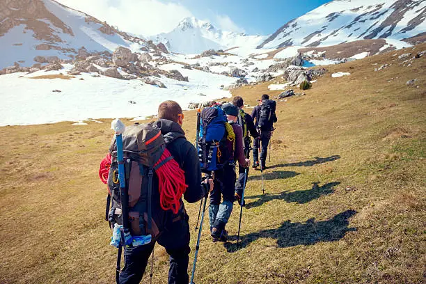 Group of mountaineers walking trough the mountains covered with snow.