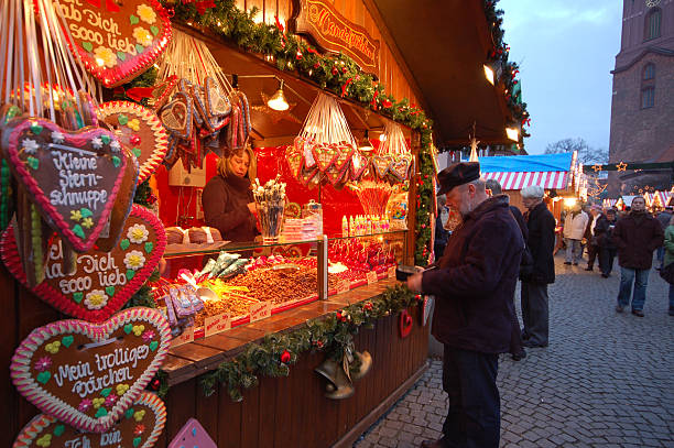 Berlin, Germany - December 6, 2008: traditional Christmans market in Berlin district Spandau (Germany). A man buying some sweets. In background other tourists visiting the market. On left side typical gingerbread hearts with german phrases like mein trolliges baerchen (my dear bear).