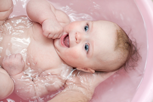 Little beautiful blue-eyed baby taking a bath