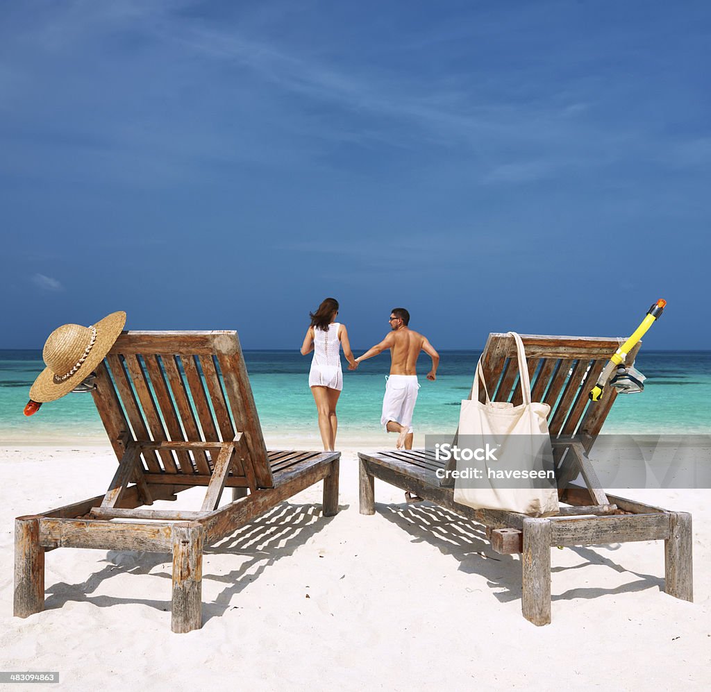 Casal em branco correndo numa praia em Maldivas - Foto de stock de Lua de mel royalty-free