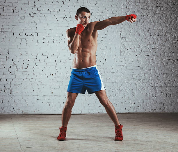 Boxer throwing jab Professional boxer standing against brick wall and throwing jab. boxing jab stock pictures, royalty-free photos & images