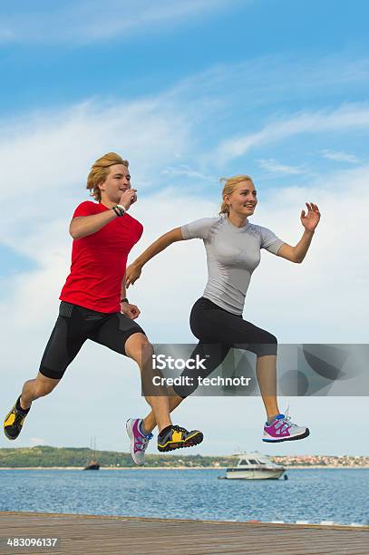 Young Couple Jogging By The Sea Stock Photo - Download Image Now - Couple - Relationship, Healthy Lifestyle, Jumping