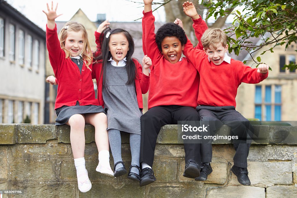 Portrait Of School Pupils Sitting On Wall Together Children Only Stock Photo