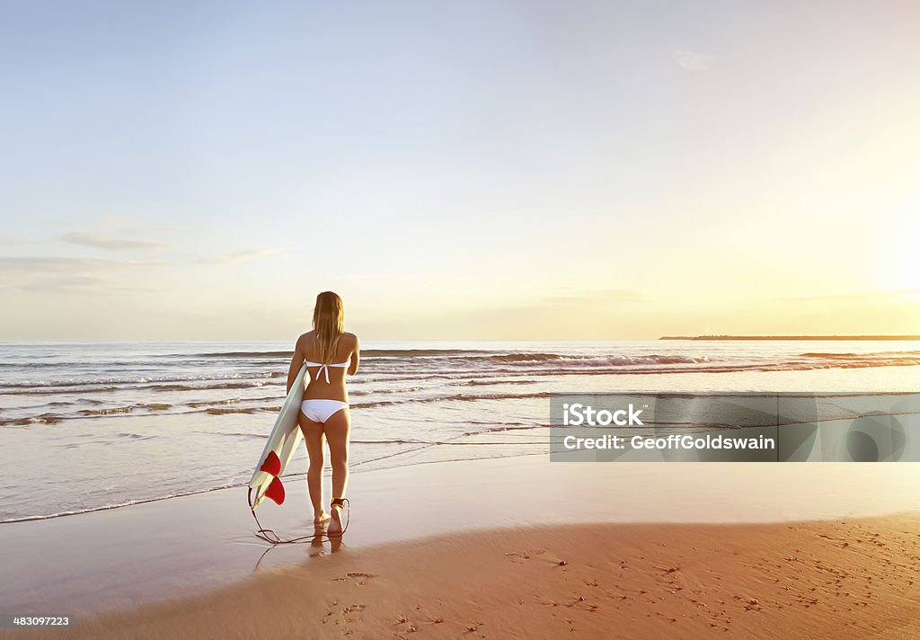 young surfer walking out to enjoy the surf at sunrise Active Lifestyle Stock Photo