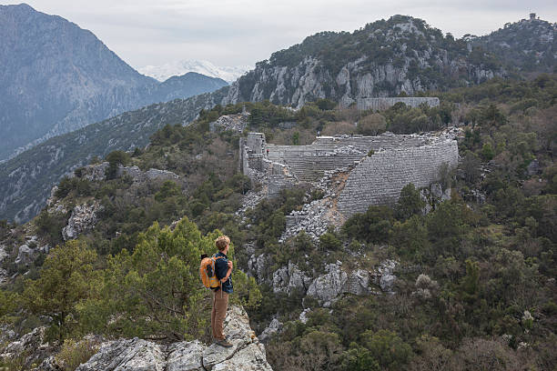 Young man hiking above theatre, ancient Greek ruin Young man hiking above theatre, ancient Greek ruin, Termessos termessos stock pictures, royalty-free photos & images