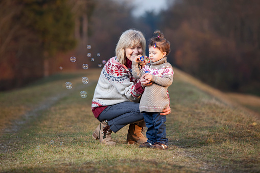 Grandmother and granddaughter blowing bubbles