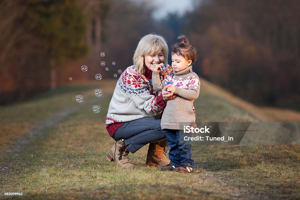 Grandmother and granddaughter blowing bubbles Bubble Wand Stock Photo