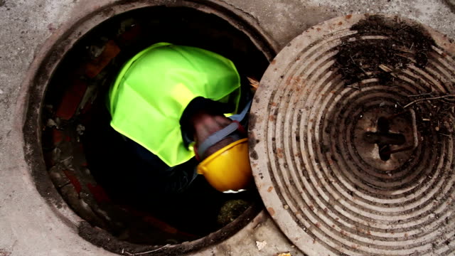 Manhole Workers Passing Each Other a Two Sided Pipe Wrench