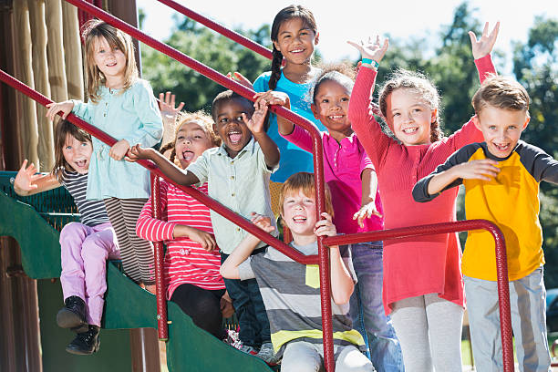 Group of multracial children waving on a playground A multi-ethnic group of children, 2 to 8 years old, hanging out together on playground equipment. They are sitting and standing on green steps, holding onto a red railing, shouting and waving. kid waves stock pictures, royalty-free photos & images
