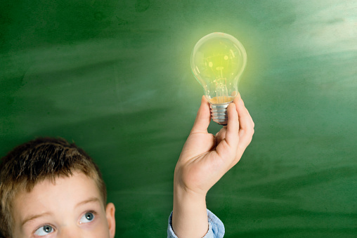 Boy with a light bulb on blackboard
