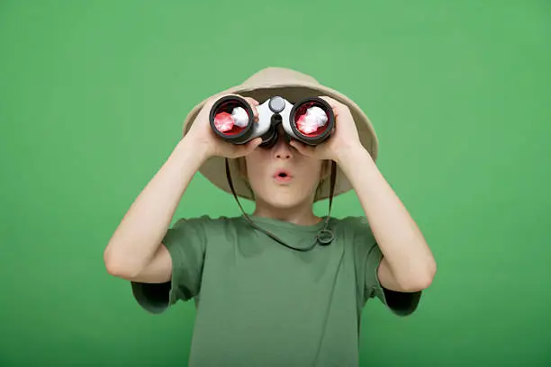 Photo of boy looking through binocular against green background