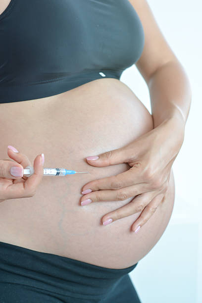 mujer embarazada con jeringa preparada para inyección en el vientre - diabetes insulin human fertility injecting fotografías e imágenes de stock