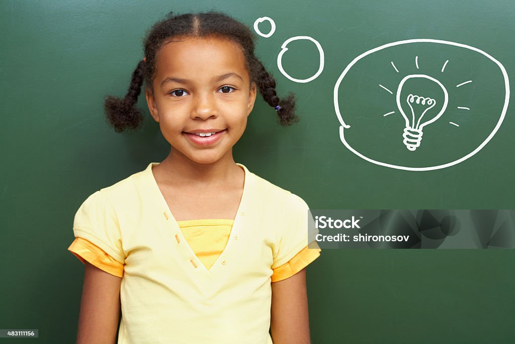 Fresh idea Portrait of smart girl by the blackboard thinking of light idea and looking at camera Dreamlike Stock Photo