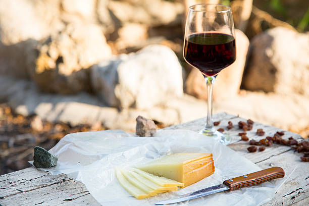 morceaux de fromage et raisins secs dans un verre à vin rouge - yellow cheese thin portion photos et images de collection